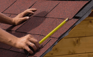 Man measuring a damaged portion of his roof
