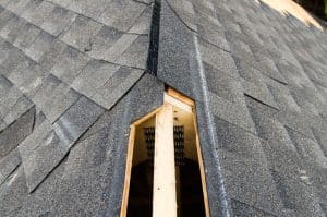 View of a partially shingled house roof, showing the cut-out for a ridge vent at the peak of the roof.