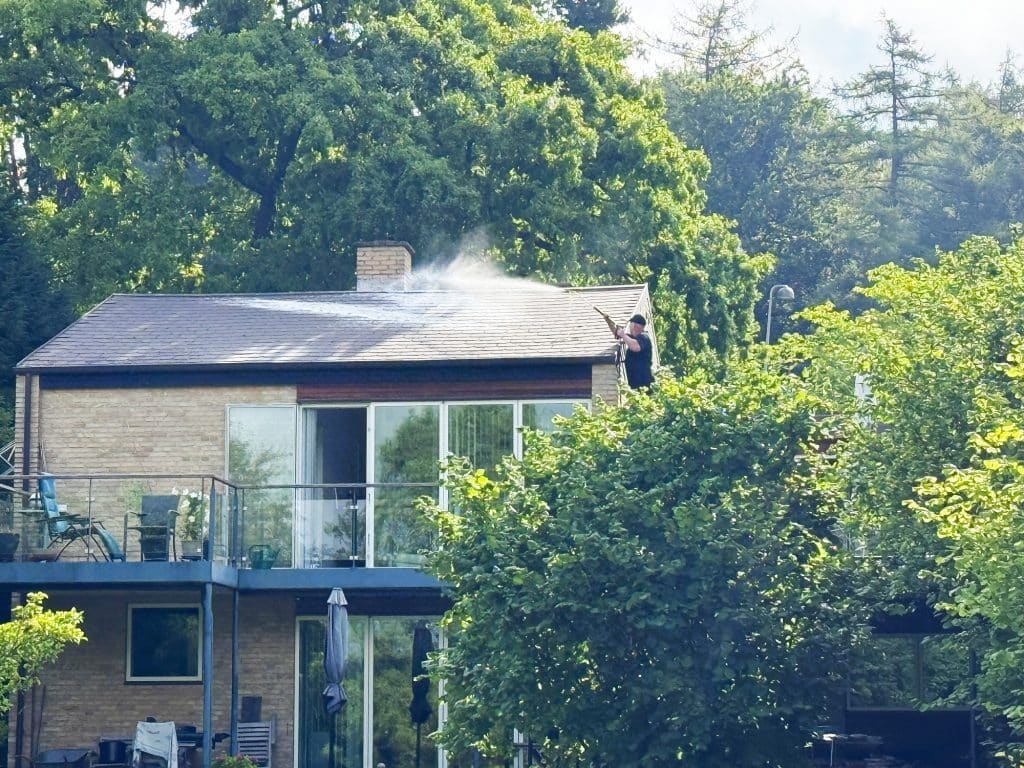 man-pressure-washing-his-shingled-roof