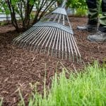 someone raking mulch away from house siding